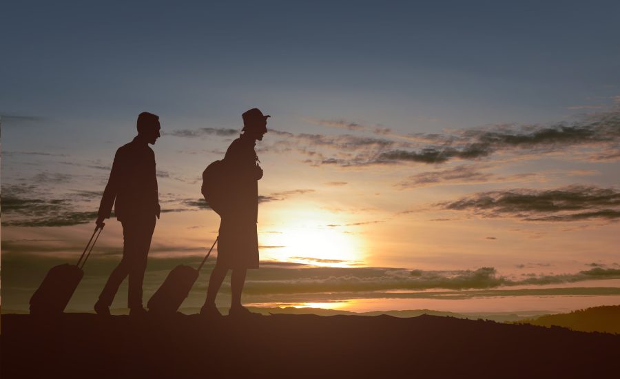 silhouette of two man with backpack and suitcase standing in the morning