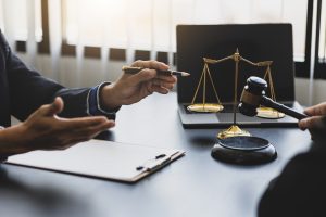 Deux personnes discutant dans un bureau avec une balance de justice et un marteau de juge sur la table.